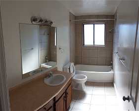 Full bathroom featuring vanity, toilet, tiled shower / bath, and tile flooring