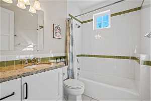 Full bathroom featuring vanity, tile floors, shower / bath combo with shower curtain, and toilet