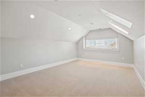 Bonus room featuring light carpet and lofted ceiling with skylight
