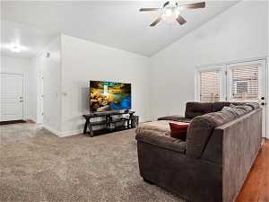 Living room with carpet flooring, high vaulted ceiling, and ceiling fan