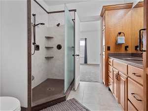 Bathroom featuring tiled shower, tile floors, vanity, and toilet