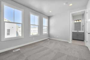 Unfurnished bedroom featuring connected bathroom, light colored carpet, and sink