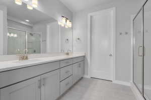 Bathroom with tile patterned flooring, double sink vanity, and a shower with shower door