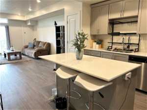Kitchen featuring sink, tasteful backsplash, gray cabinetry, stainless steel dishwasher, and light hardwood / wood-style flooring