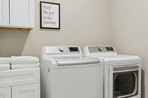 Washroom with washer and dryer and cabinets