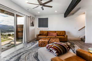 Living room featuring a mountain view. ceiling fan, and beamed ceiling