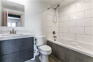 Full bathroom with tiled shower / bath, toilet, oversized vanity, and tile flooring