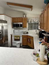 Kitchen with backsplash, vaulted ceiling, stainless steel appliances, and sink