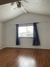 Spare room with vaulted ceiling with beams, ceiling fan, and hardwood / wood-style flooring