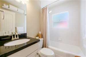 Full bathroom with large vanity, toilet, and shower / bath combo with shower curtain