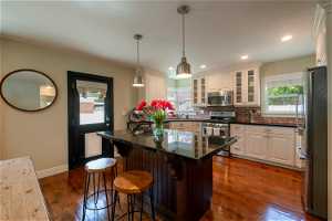 Kitchen with backsplash, pendant lighting, stainless steel appliances, and dark hardwood / wood-style flooring