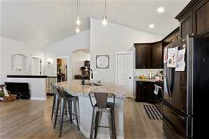 Kitchen featuring dark brown cabinets, light wood-type flooring, stainless steel appliances, and lofted ceiling