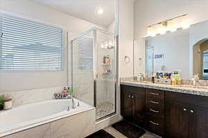 Bathroom featuring double vanity, independent shower and bath, and tile floors