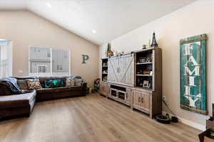 Living room with lofted ceiling and light hardwood / wood-style flooring