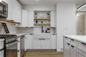 Kitchen with appliances with stainless steel finishes, backsplash, and light hardwood / wood-style flooring