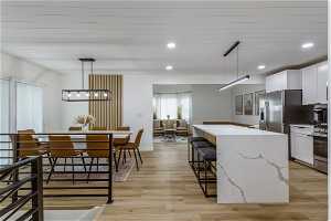 Kitchen with white cabinets, light hardwood / wood-style flooring, and decorative light fixtures