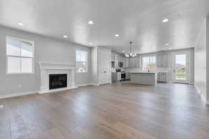 Unfurnished living room with a notable chandelier, light hardwood / wood-style flooring, and a wealth of natural light