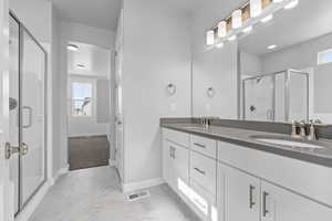 Bathroom with dual vanity, tile patterned floors, and an enclosed shower