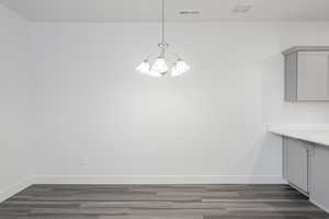 Unfurnished dining area featuring dark hardwood / wood-style flooring and an inviting chandelier