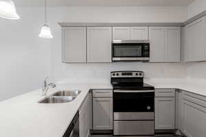 Kitchen featuring gray cabinetry, appliances with stainless steel finishes, sink, and decorative light fixtures