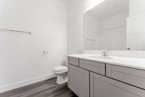 Bathroom with toilet, a shower, vanity, and wood-type flooring