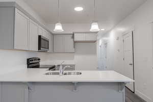 Kitchen with a breakfast bar, dark hardwood / wood-style floors, sink, pendant lighting, and stainless steel appliances