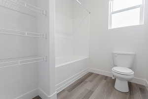 Bathroom featuring toilet, shower / washtub combination, and hardwood / wood-style floors