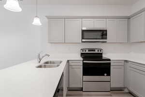 Kitchen featuring light hardwood / wood-style flooring, appliances with stainless steel finishes, sink, and hanging light fixtures