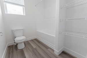 Bathroom featuring  shower combination, wood-type flooring, and toilet