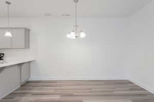 Unfurnished dining area with a chandelier and light wood-type flooring