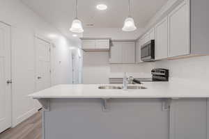 Kitchen with electric range oven, sink, hanging light fixtures, and a breakfast bar