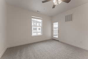 Carpeted spare room featuring ceiling fan and plenty of natural light