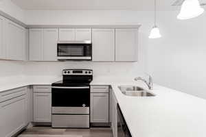 Kitchen featuring gray cabinets, sink, hanging light fixtures, and stainless steel appliances