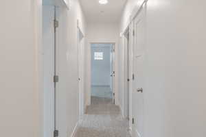 Corridor featuring light colored carpet