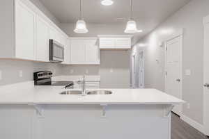 Kitchen with white cabinets, decorative light fixtures, sink, and electric range oven