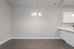 Unfurnished dining area with a notable chandelier and dark hardwood / wood-style flooring