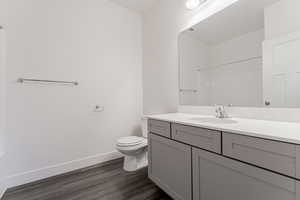 Bathroom featuring wood-type flooring, vanity, toilet, and walk in shower