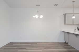 Unfurnished dining area with light hardwood / wood-style floors, a notable chandelier, and sink