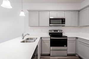 Kitchen featuring hanging light fixtures, dark hardwood / wood-style flooring, appliances with stainless steel finishes, gray cabinets, and sink