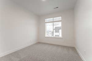 Carpeted empty room featuring vaulted ceiling