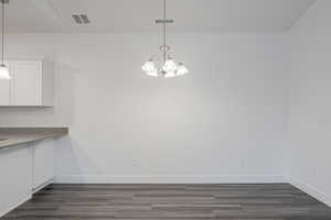 Unfurnished dining area with an inviting chandelier and dark hardwood / wood-style flooring