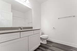 Bathroom with vanity, toilet, hardwood / wood-style flooring, and walk in shower