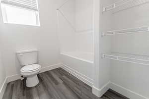 Bathroom featuring wood-type flooring, toilet, and bathing tub / shower combination