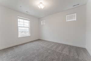 Empty room with carpet and a textured ceiling