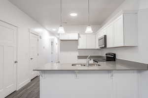 Kitchen featuring white cabinets, dark hardwood / wood-style flooring, a breakfast bar, electric stove, and decorative light fixtures