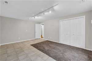 Unfurnished bedroom with a closet, light tile floors, and track lighting