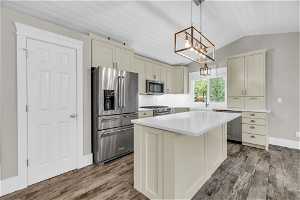 Kitchen featuring a center island, high quality appliances, backsplash, decorative light fixtures, and wood-type flooring
