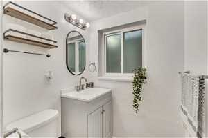 Bathroom with toilet, oversized vanity, and a textured ceiling