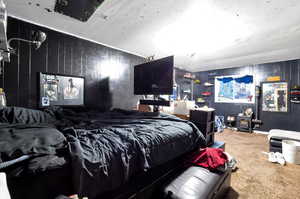 Carpeted bedroom featuring wooden walls