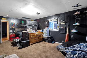 Carpeted bedroom featuring wooden walls